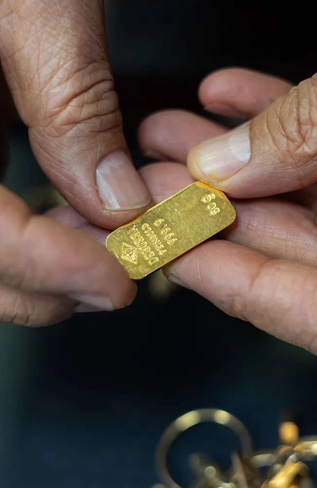 Nahaufnahme eines Goldbarrens, der von einem Juwelier gehalten wird